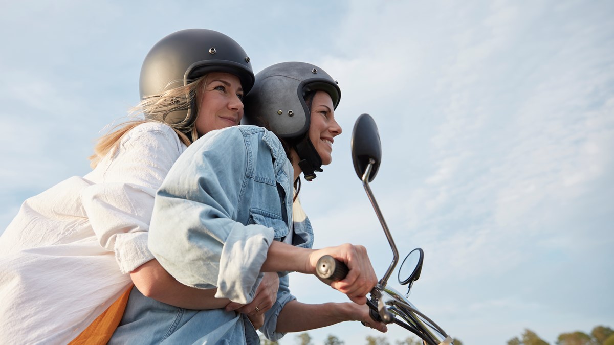 Två ungdomar som åker tillsammans på en moped. 